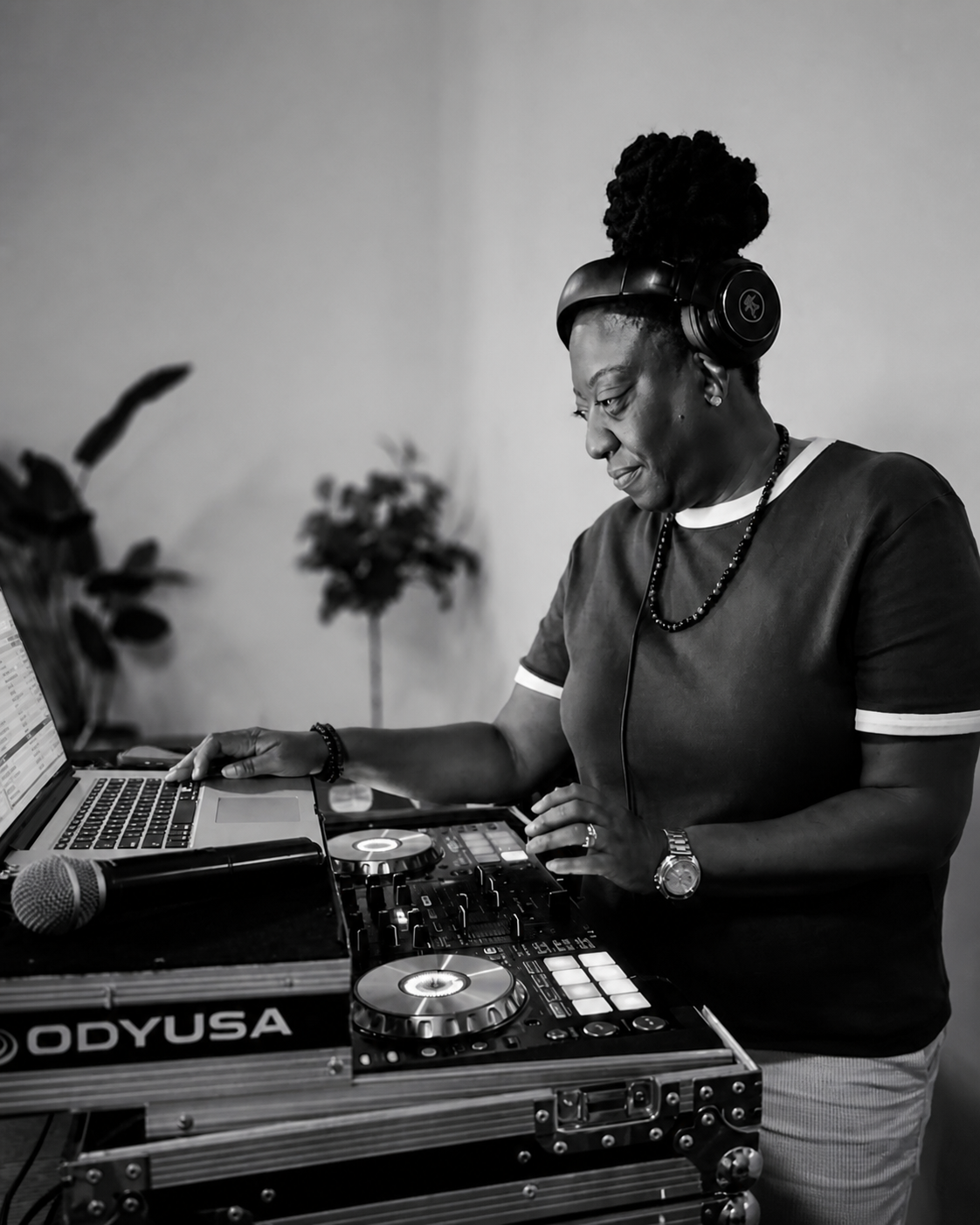 DJ JJ Rock at her controller and laptop, wearing headphones — black-and-white portrait